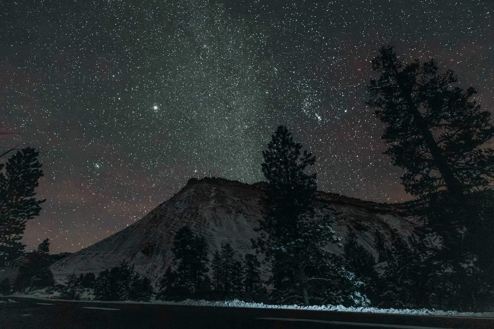 A starry night sky over a snowy mountain landscape